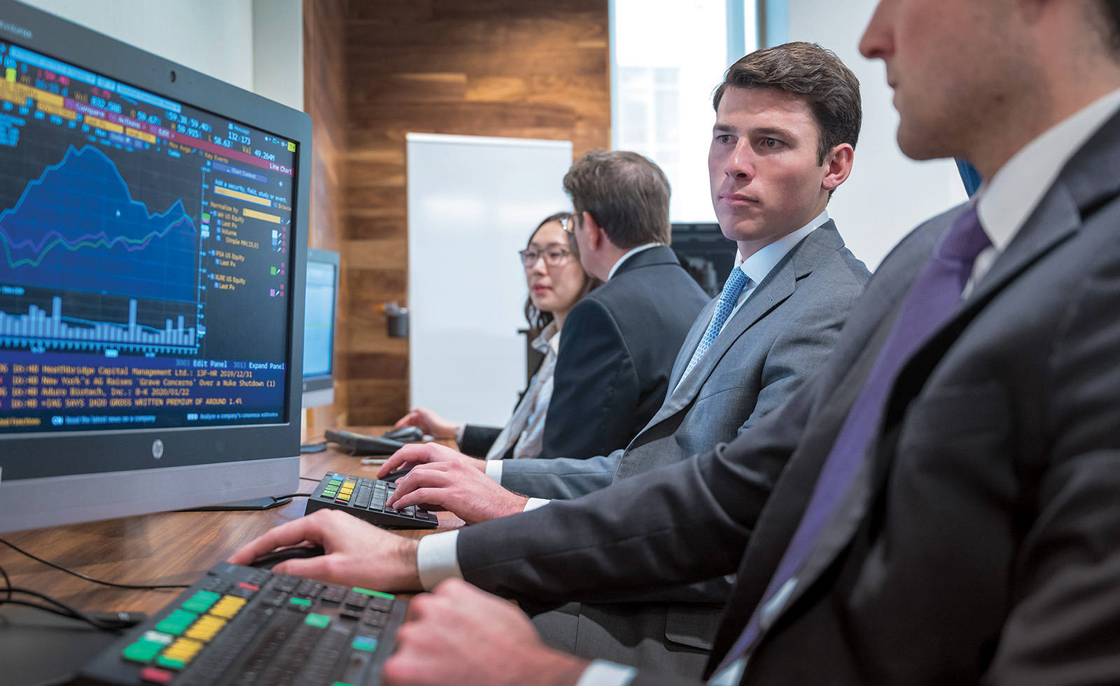 Man in suit looks at a screen with financial data