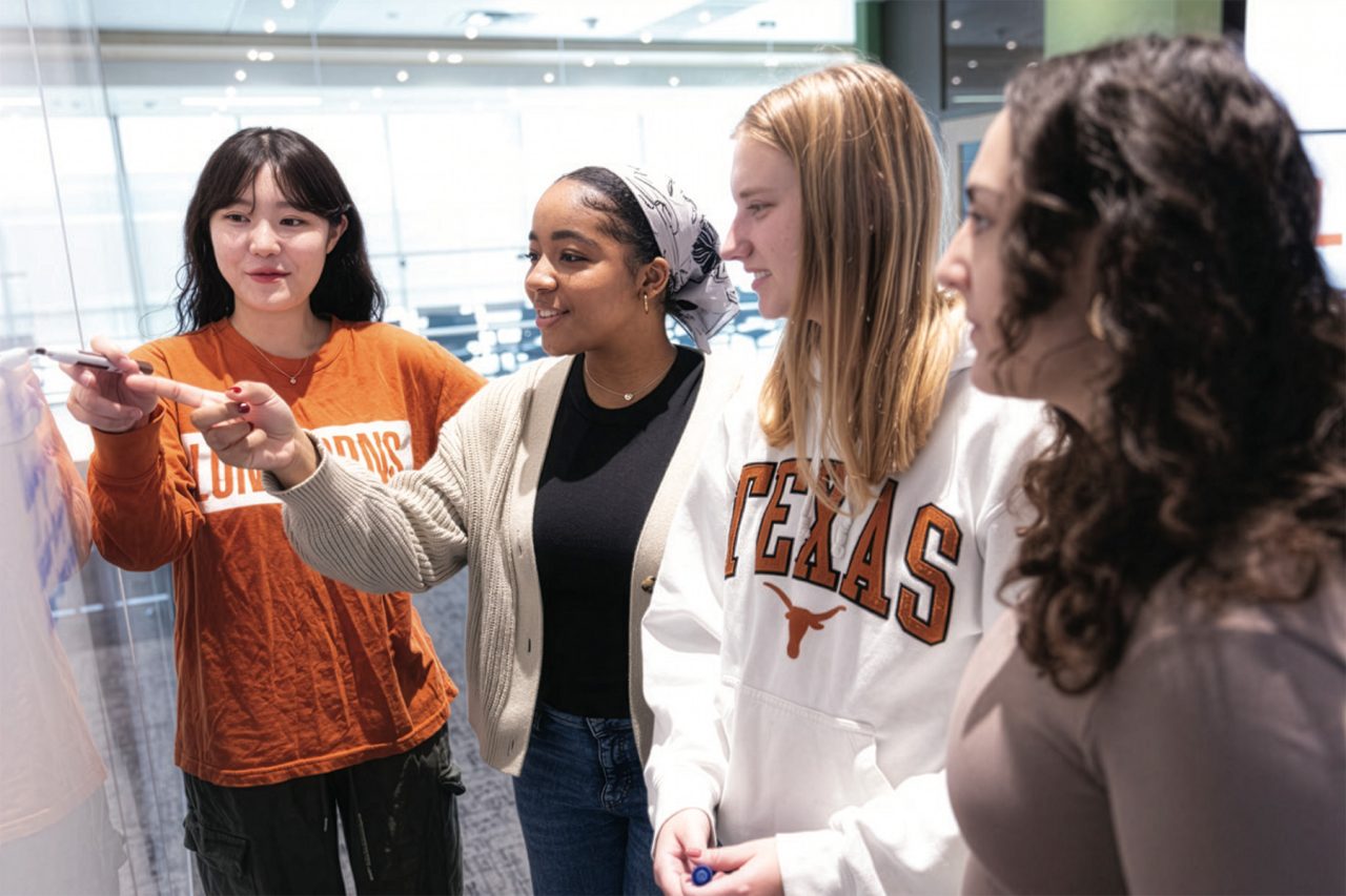 Four students look at a whiteboard